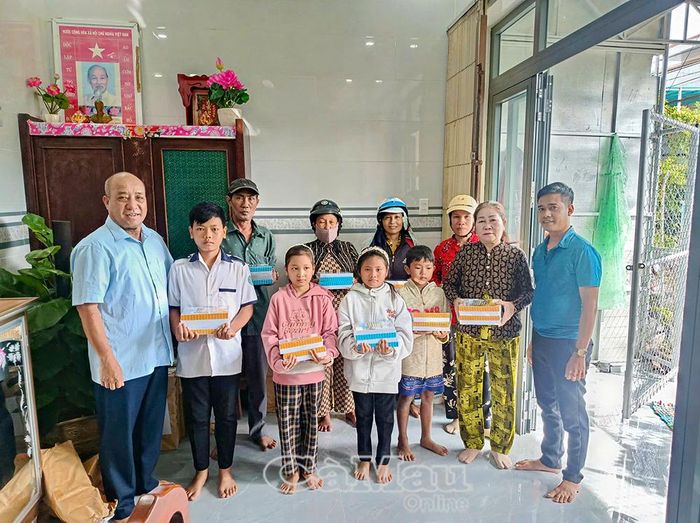 Ông Phạm Tiến Nguyên (bìa trái), Trưởng ban đại diện cha mẹ học sinh Trường THPT Võ Văn Kiệt, trao tập hỗ trợ học sinh có hoàn cảnh khó khăn trước thềm năm học mới.