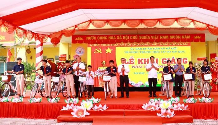 Các đồng chí lãnh đạo xã Mỹ Đức tặng xe đạp cho học sinh Trường THCS Mỹ Đức. Ảnh: Biên Phạm