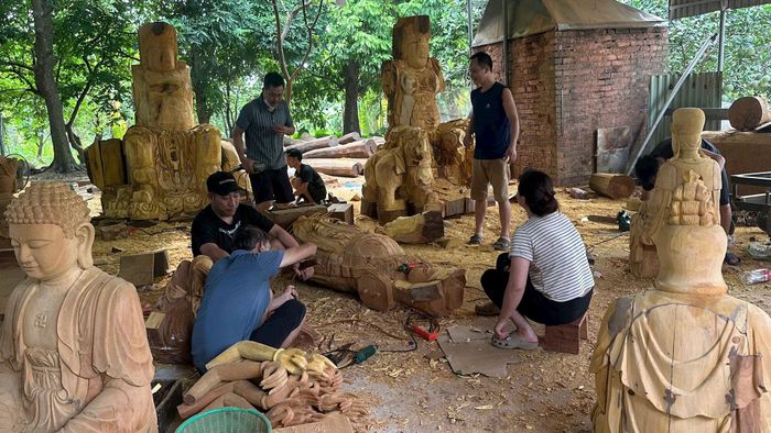 Những người thợ trong xưởng điêu khắc của Nghệ nhân Nguyễn Văn Trúc đang miệt mài trao đổi công việc. Ảnh: PV