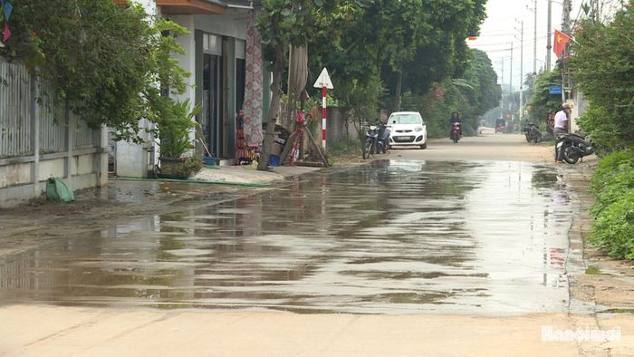 Nhiều hộ dân phải thường xuyên tưới nước để hạn chế bụi từ đường. Ảnh: Thái Trọng.