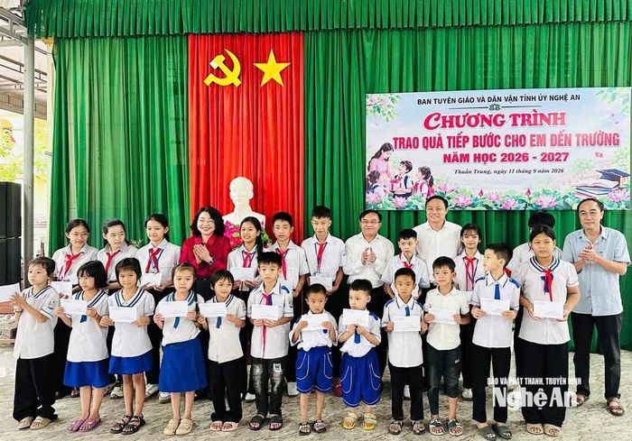 Các đại biểu và các em học sinh chụp ảnh lưu niệm.