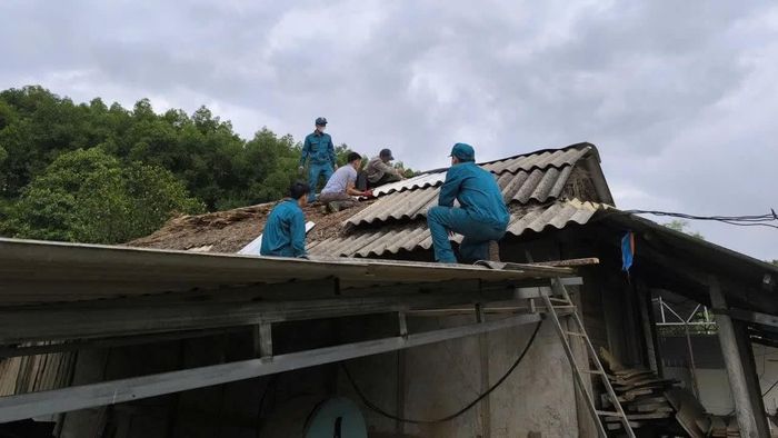 Cán bộ, chiến sĩ và lực lượng dân quân giúp lợp lại mái nhà cho các hộ dân.