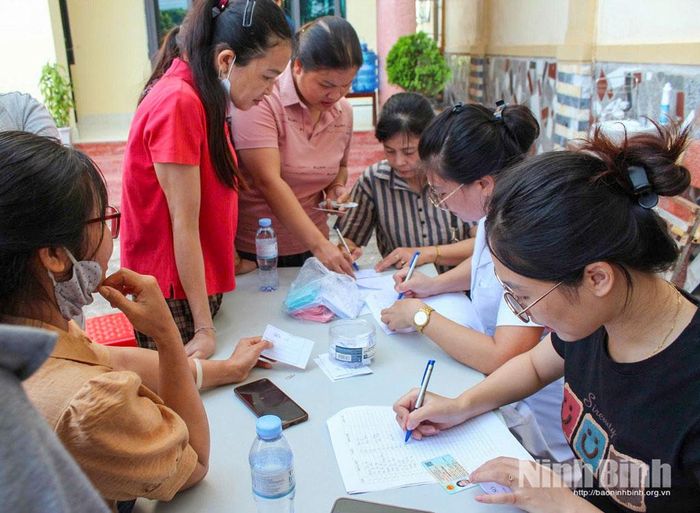 Viên chức phụ trách dân số và cộng tác viên dân số xã Giao Hoà hỗ trợ phụ nữ xã đăng ký thăm khám phụ khoa trong Chiến dịch chăm sóc sức khoẻ sinh sản. Ảnh: Lan Anh