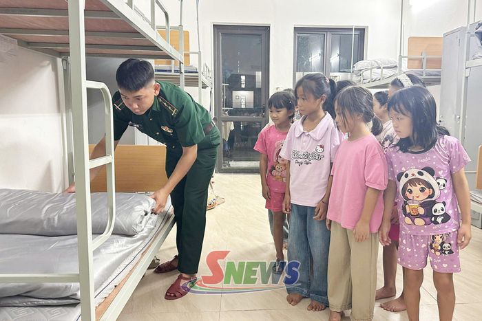 Cán bộ, đoàn viên thanh niên Đồn Biên phòng Cửa khẩu Chiềng Khương hướng dẫn học sinh cách gấp chăn màn. 