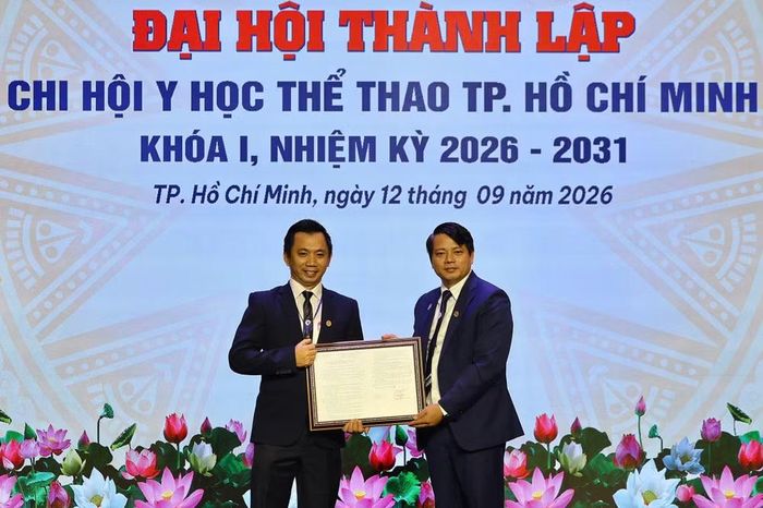Tiến sĩ Nguyễn Mạnh Thắng, Chủ tịch Hội Y học thể thao Việt Nam (bên phải) trao quyết định thành lập Chi hội Y học Thể thao Thành phố Hồ Chí Minh. (Ảnh: TRỌNG ANH)