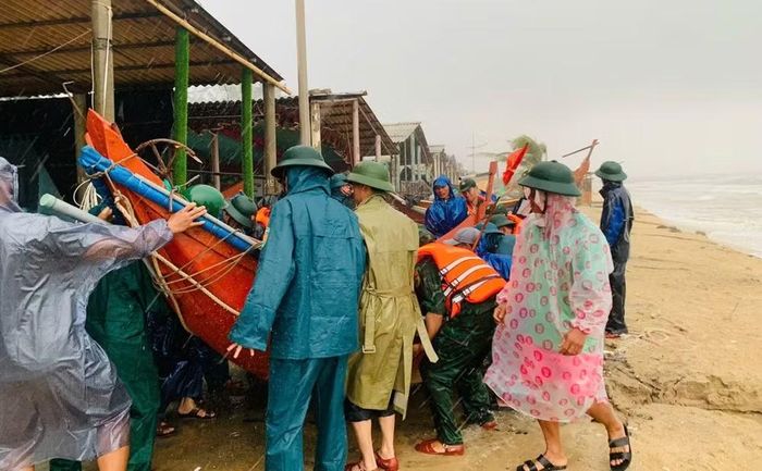 Lực lượng chức năng cùng người dân di dời ghe, thuyền, ngư lưới cụ ra khỏi khu vực bị sóng xâm thực. (Ảnh: H.M)