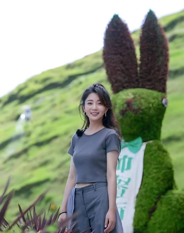 Bộ trang phục này lấy tông màu xám đậm làm chủ đạo. Hãy bắt đầu với chiếc áo thun. Phần cổ áo được thiết kế kín đáo, chỉ để lộ vùng cổ và xương quai xanh. Dù không có kiểu vai trễ, phom dáng áo vẫn khéo léo che đi phần mỡ thừa dưới cánh tay. Phần tay ngắn ôm vừa vặn tạo nên sự cân bằng hoàn hảo: Vừa tôn lên những đường cong cơ thể, vừa mang lại cảm giác thoải mái, không gây bó sát hay khó chịu cho da. Áo có thiết kế dáng lửng (crop-top), để lộ phần eo khi đứng. Chiếc quần tạo nên ấn tượng thị giác đầy cuốn hút. Chất liệu vải với kết cấu bề mặt nổi bật giúp nâng tầm phong cách ngay tức thì. Điểm nhấn nằm ở phần cạp quần, nơi có một lớp vải mỏng nhẹ bao phủ khoảng một phần ba diện tích bề mặt. Nhờ chất liệu thanh mảnh, lớp vải này khẽ lay động theo từng bước chân, mang lại vẻ đẹp đầy duyên dáng và gợi cảm.