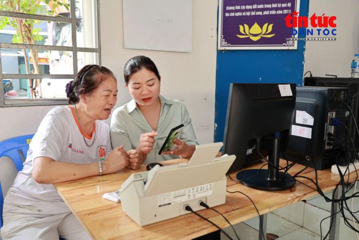 Bà Đỗ Thị Lục (bên trái), sinh năm 1949, tìm hiểu cách thực hiện thủ tục hành chính trực tuyến tại điểm hỗ trợ ở Khu phố 13 và 14, phường Tân Bình.
