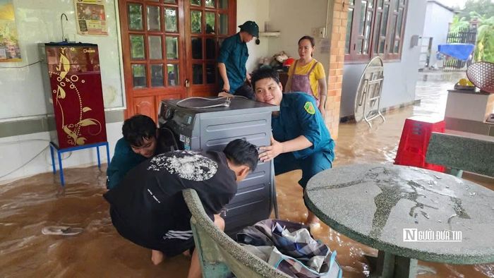 Người dân được lực lượng chức năng hỗ trợ di dời tài sản, di chuyển qua khu vực ngập.
