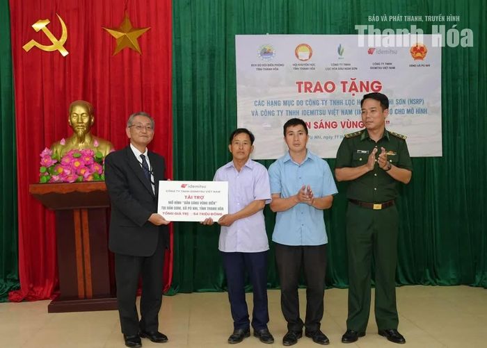 Đại diện lãnh đạo Công ty TNHH Idemitsu Việt Nam trao biểu trưng tài trợ công trình đèn năng lượng mặt trời cho Ban quản lý bản Cơm.