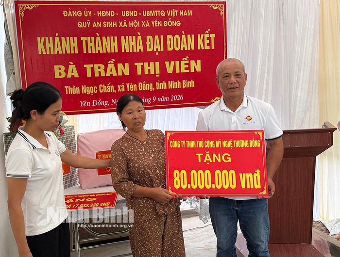 Đại diện Công ty TNHH Thủ công Mỹ nghệ Thượng Đồng (xã Vạn Thắng) trao biển biểu trưng kinh phí hỗ trợ xây dựng nhà "Đại đoàn kết" cho gia đình bà Trần Thị Viền.