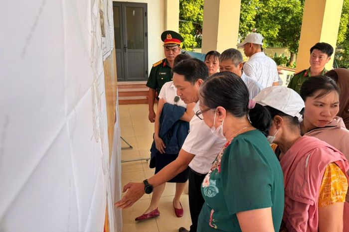 Lãnh đạo UBND xã Vĩnh Thanh hướng dẫn người dân tìm hiểu hồ sơ, xem bản đồ và thực hiện việc góp ý tại điểm nhà văn hóa thôn Yên Hà. Ảnh: Lý Thanh