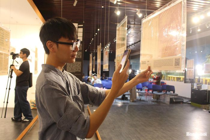 Sinh viên Nguyễn Quốc Anh trải nghiệm tra cứu thông tin và thưởng thức các bản nhạc qua mã QR tại triển lãm. Ảnh: Vi Giáng