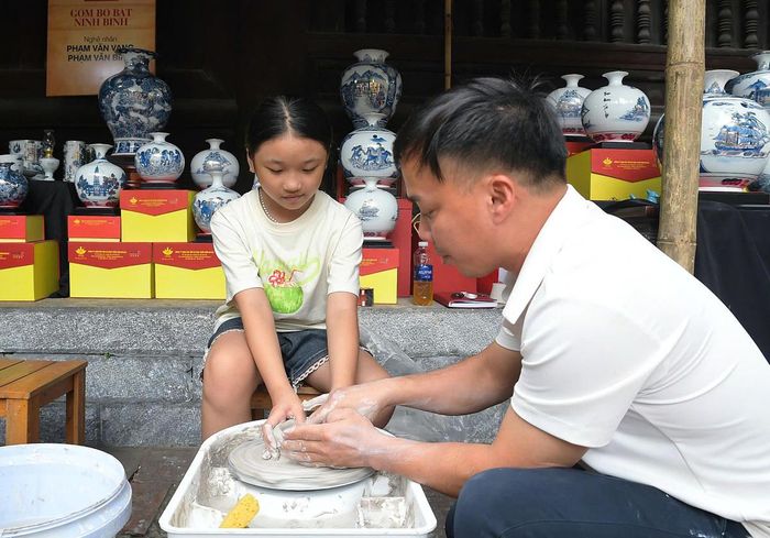 Nghệ nhân làng gốm Bồ Bát đến từ Ninh Bình hướng dẫn em nhỏ trải nghiệm làm gốm.