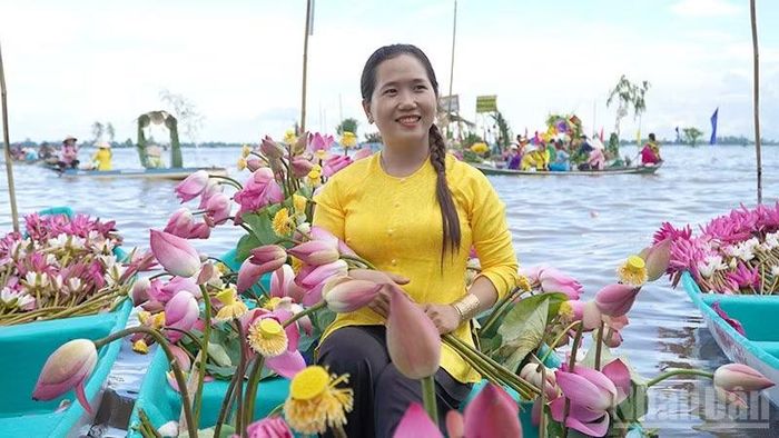 Duyên dáng bên chiếc xuồng sen trên cánh đồng mùa nước nổi. (Ảnh: HỮU NGHĨA)