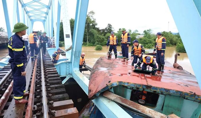 Lực lượng chức năng tiến hành cắt phần mái sà lan bị mắc kẹt với cầu đường sắt. (Ảnh: Công an tỉnh Quảng Trị)