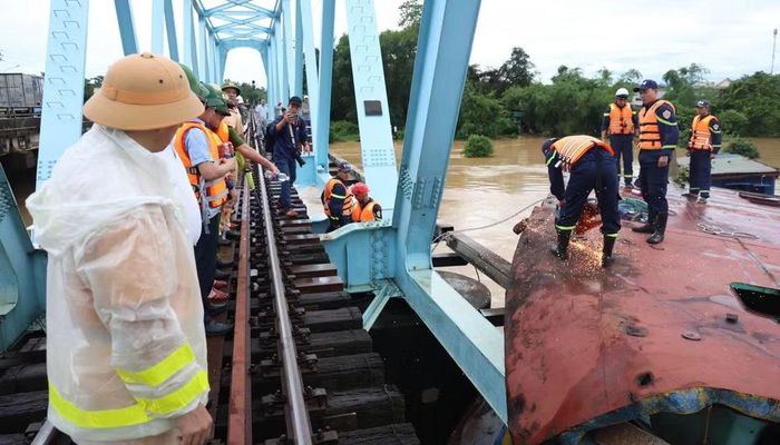 Lực lượng chức năng tiến hành cắt phần mái sà-lan bị mắc kẹt với cầu đường sắt. (Ảnh: Công an tỉnh Quảng Trị)