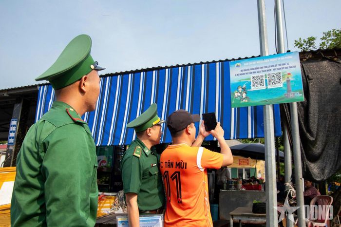 Cán bộ, chiến sĩ Ban chỉ huy Bộ đội Biên phòng thành phố Hải Phòng thông tin và hướng dẫn ngư dân sử dụng mã “QR kép”.