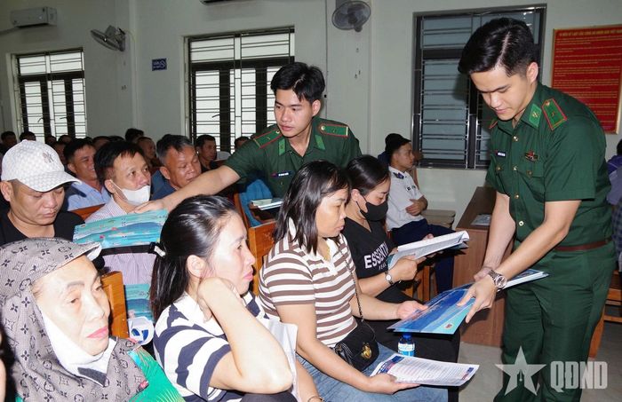 Cán bộ Đồn Biên phòng Tràng Cát phát tờ rơi cho ngư dân.