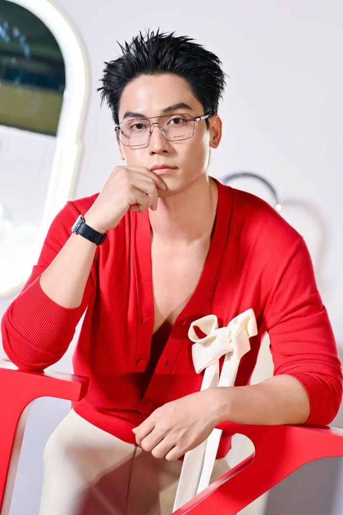 Võ Điền Gia Huy diện cardigan đỏ cổ sâu, phối quần sáng màu. Anh tạo điểm nhấn trang phục với nơ trắng lớn cài trước ngực. Nam diễn viên kết hợp kính gọng trong, đồng hồ dây đen và tóc vuốt dựng.