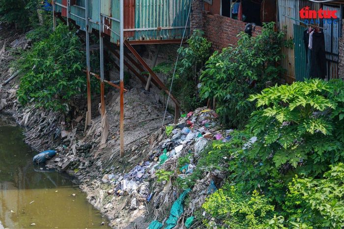 Rác thải nằm xen lẫn với lều lán, nhà xưởng, khiến cảnh quan ven sông trở nên nhếch nhác và ô nhiễm.