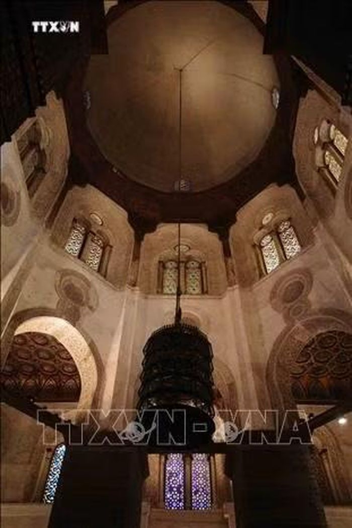 Mái vòm bên trong lăng mộ của Sultan Qalawun trong quần thể. Chiếc đèn lồng kim loại lớn nhiều tầng treo giữa khung cảnh, thả dây dài từ đỉnh vòm xuống gần khu mộ, là kiểu đèn chùm truyền thống thường thấy trong các lăng mộ Mamluk để chiếu sáng không gian thiêng phía trên các ô cửa sổ kính màu. Phía dưới, các cửa sổ kính màu hình học nhiều lớp (loại đặc trưng Mamluk, ghép từ thạch cao đục lỗ và kính màu) chiếu ánh sáng vào không gian nơi đặt ngôi mộ trống bằng gỗ tượng trưng. Ảnh: Hoàng Nhật/PV TTXVN tại Ai Cập