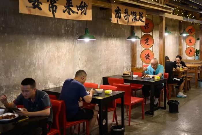 Những người đàn ông dùng bữa một mình tại nhà ăn cộng đồng Thành phố ngầm Shancheng Memory ở Trùng Khánh, Trung Quốc. Ảnh: Getty.