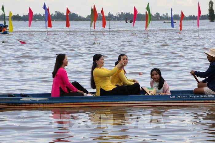 Du khách hào hứng trải nghiệm đi xuồng trên đồng mùa nước nổi. Ảnh: Hồng Thái - TTXVN