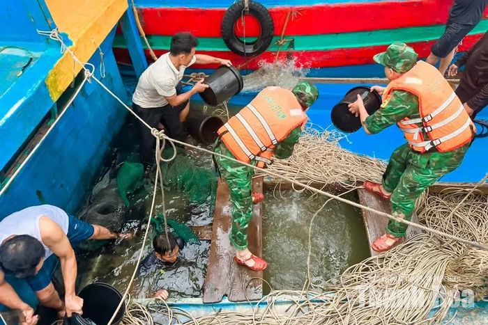 Cán bộ, chiến sĩ Đồn Biên phòng Hải Hòa cùng người dân khẩn trương tát nước, khắc phục sự cố trên tàu cá TH-91594-TS.