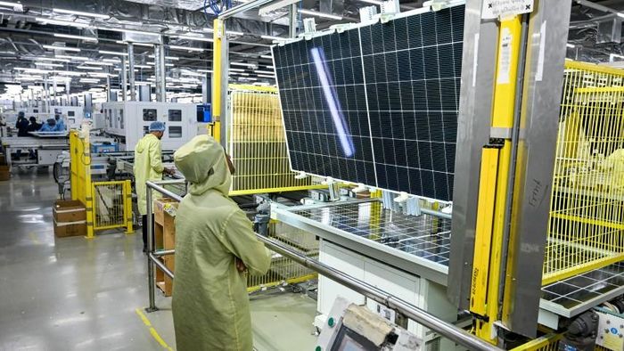 Các nhân viên đang kiểm tra các tấm pin năng lượng mặt trời trên dây chuyền lắp ráp tại một nhà máy của Adani Group. Ảnh: AFP/FILE
