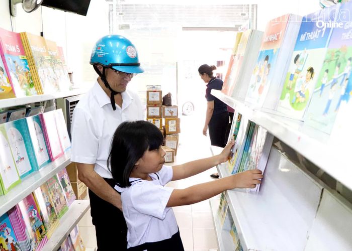Phụ huynh và học sinh mua sách giáo khoa tại một cửa hàng sách và thiết bị trường học.