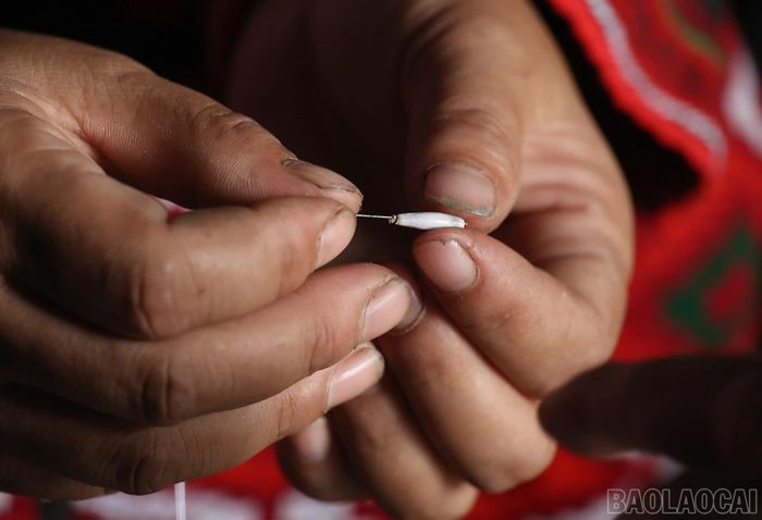 Người Xá Phó tỉ mỉ xâu từng hạt cườm để đính lên vải dệt thủ công bằng sợi bông nhuộm chàm.