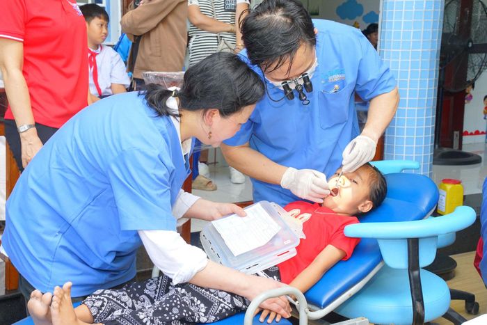 Các y bác sĩ khám răng miệng cho các em nhỏ