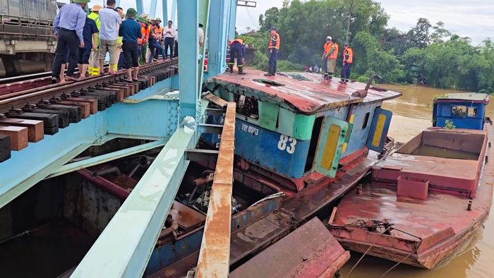Ca bin của chiếc sà lan lớn còn nổi mắc kẹt dưới cầu bị móp méo và làm hư hỏng lan can của cầu đường sắt. Lực lượng chức năng tiến hành cưa cắt phần ca bin của sà lan đang dính chặt vào lan can cầu.