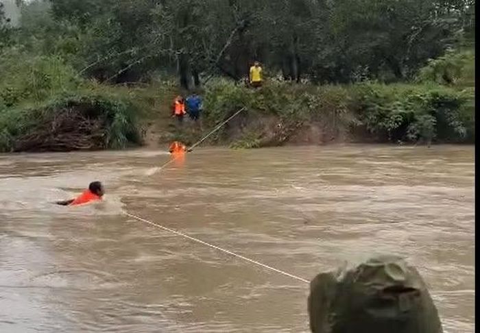 Duy (dưới sông, sát bờ) đỡ, đưa từng nhân viên đo đạc dự án hồ Ka Pét qua dòng nước lũ.