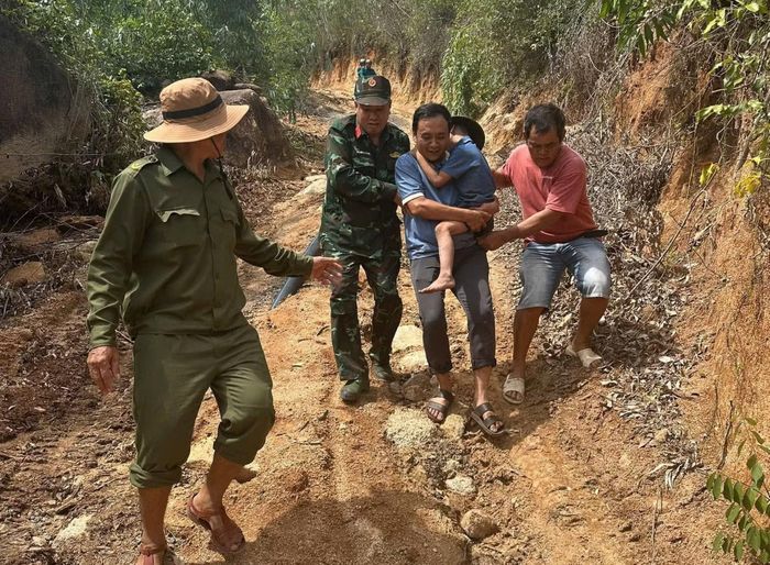 Trung tá Nguyễn Vũ Thành, Phó trưởng Công an phường Sông Cầu (áo thun xanh) - người bế cháu Nguyễn Gia K cùng các lực lượng Quân sự, dân quân đưa đứa trẻ đi lạc xuống chân núi Ông Định.