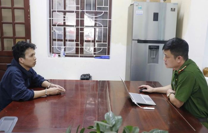 Điều tra viên lấy lời khai Nguyễn Văn Tuấn - đối tượng chủ mưu, cầm đầu ổ nhóm đánh bạc và rửa tiền trên không gian mạng.