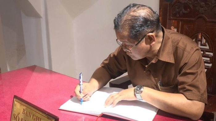 Chủ tịch Ủy ban Chính quyền huyện Lạ Màm Bua-lay Vị-lay-vông ghi sổ lưu niệm trong chuyến thăm Tượng đài Mẹ Việt Nam Anh hùng.