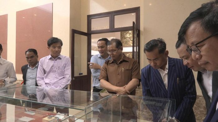 Đoàn đại biểu cấp cao huyện Lạ Màm nghe giới thiệu về các tư liệu, kỷ vật trưng bày bên trong Nhà tưởng niệm."