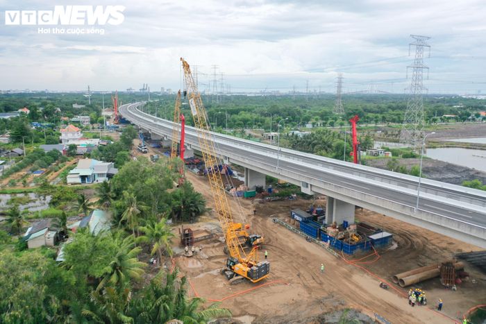 Xe ben, máy xúc, xe lu, cần cẩu và máy khoan cọc nhồi liên tục di chuyển trên công trường. Từng tốp công nhân đang gia công, buộc cốt thép lồng, chuẩn bị cho việc thi công móng cọc.