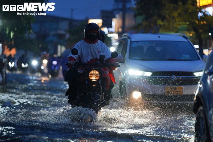 Đến hơn 18h, mưa lớn xuất hiện đúng lúc triều cường đạt đỉnh, khiến đường Trần Xuân Soạn ngập sâu, người dân đi lại khó khăn.
