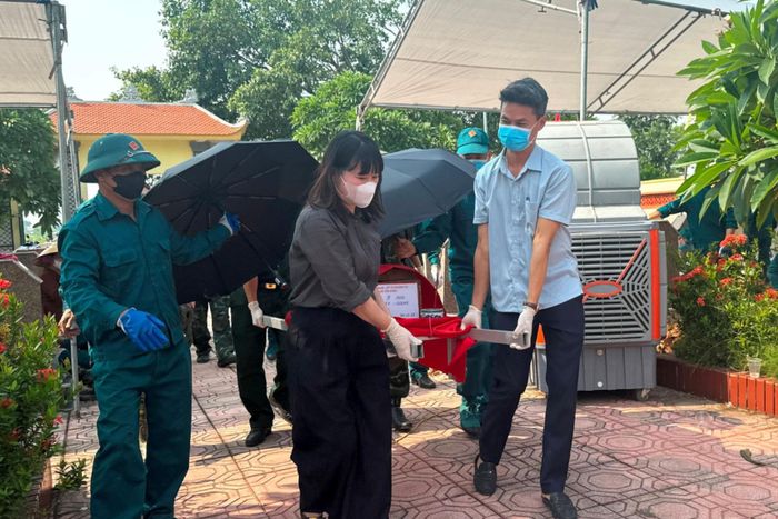 Phó Chủ tịch UBND xã Vân Đình Phạm Thúy Hòa cùng các lực lượng trang trọng đưa hài cốt liệt sĩ về khu vực lấy mẫu sinh phẩm. Ảnh: Mai Hoa