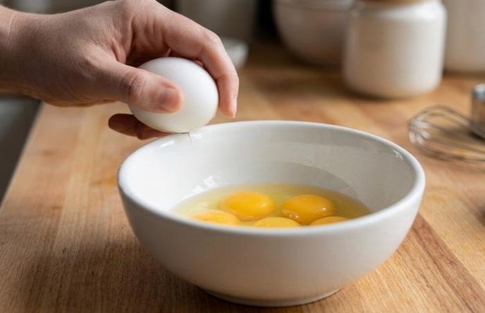 Đập trứng vào mép bát là một thói quen sai lầm phổ biến khiến vỏ trứng bị vụn và rơi vào bên trong bát.