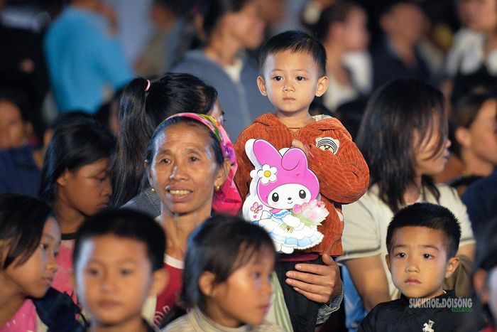 Một em nhỏ chăm chú theo dõi chương trình từ vòng tay người thân. Ảnh: Tuấn Anh