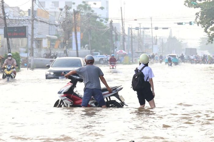 Một phụ huynh đưa con đi học nhưng xe bị chết máy do triều cường ngập sâu ở đường Cách Mạng Tháng Tám, TP. Cần Thơ vào ngày 14.9