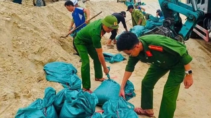 Lực lượng của Công an xã Lệ Thủy được huy động lấy cát từ đồi cát ven biển để chuyển về đắp vá, khắc phục tạm sự cố, (Ảnh: LT)