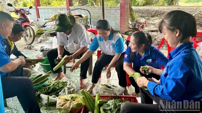 Lực lượng đoàn viên thanh niên và người dân chuẩn bị cơm cho cán bộ, chiến sĩ giúp dân thu hoạch lúa. (Ảnh: THANH PHONG)