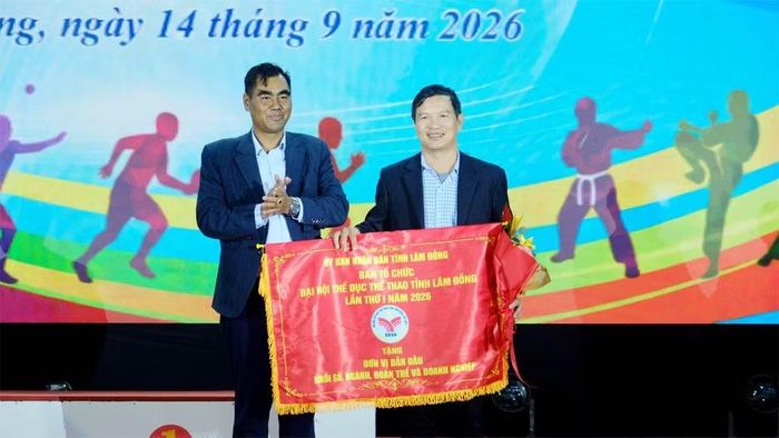 Phó Chủ tịch Ủy ban Mặt trận Tổ quốc Việt Nam tỉnh Lâm Đồng Bon Yô Soan trao tặng Cờ đơn vị dẫn đầu khối sở, ngành, đoàn thể và doanh nghiệp cho Sở Giáo dục và Đào tạo. (Ảnh: V.Q)