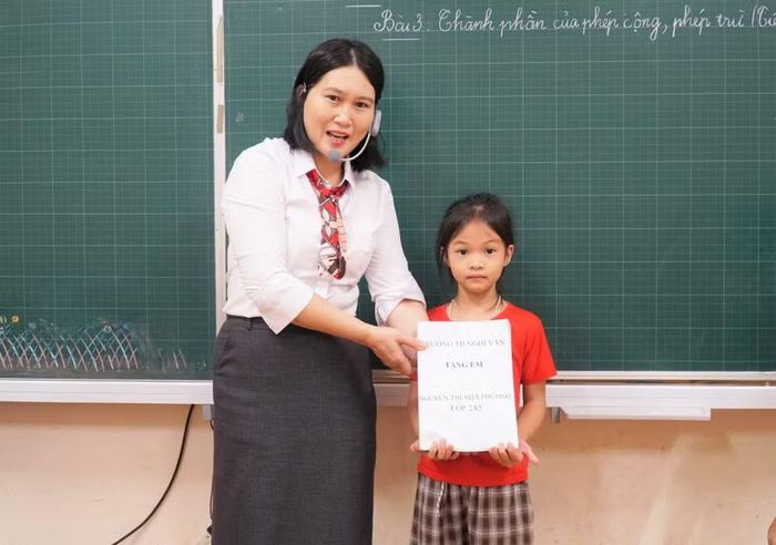 Cô giáo trao sách của các bạn học sinh quyên góp cho em Nguyễn Thị Nhã Phương, lớp 2A5 Trường Tiểu học Nghi Văn. Ảnh: Hồ Lài