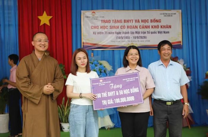 Nhà tài trợ trao bảng tượng trưng 100 thẻ BHYT và 50 suất học bổng.